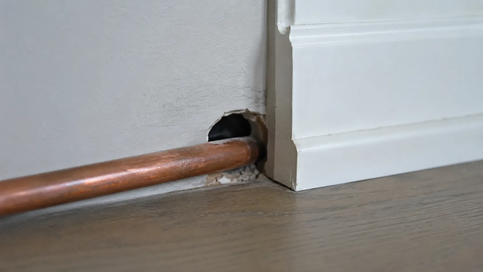 Petit passage utilisé par une souris autour d’un tuyau dans un mur